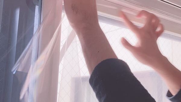 結露防止フィルムを窓に貼る男性の手